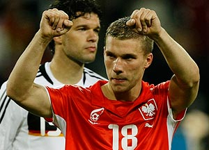 Germany's Lukas Podolski (R), wearing a Polish football shirt, celebrates as team mate Michael Ballack walks behind him after their Group B Euro 2008 soccer match victory against Poland 